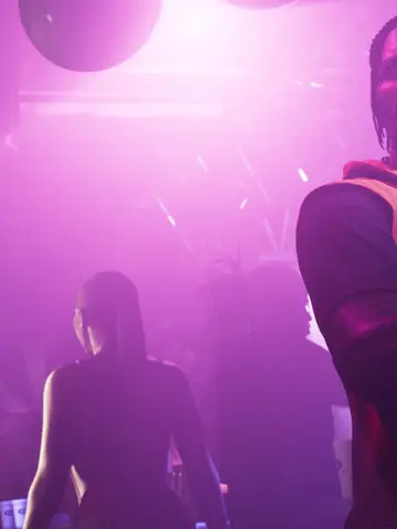 Dre'Quan Priest standing in a purple-lit club